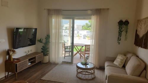 a living room with a couch and a tv at בית האורחים - צימר גלילי בין שדות ונחלים in Sede Neẖemya