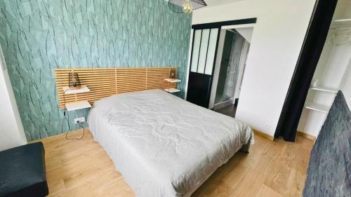 a bedroom with a bed and a green wall at Maison familiale proche de la mer in Surtainville