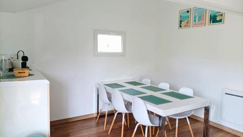 a dining room with a green and white table and chairs at Maison familiale proche de la mer in Surtainville