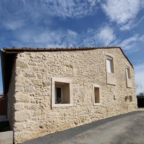 a stone building with three windows on the side at Le Logis de Jade in Saint-Léon