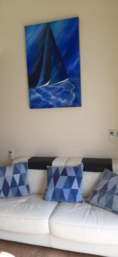 a white couch with blue pillows sitting under a painting at Zeepieper in Bredene