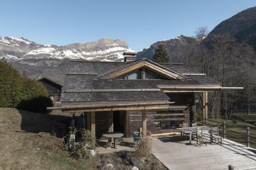 une cabane en rondins dans les montagnes avec une table et des chaises dans l'établissement Chalet L'Oratoire & Mazot - Renovated Historic Chalet - Huge Garden & Separate Cabin for 2, aux Houches