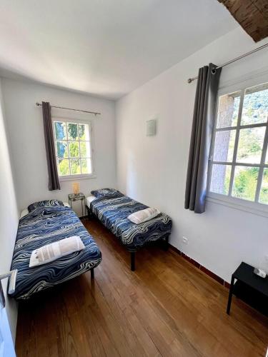 deux lits dans une chambre avec deux fenêtres dans l'établissement Havre de paix proche de Nice, à Falicon