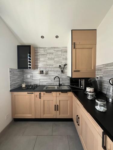 une cuisine avec des armoires en bois et un comptoir noir dans l'établissement Maison proche centre-ville, à Dijon