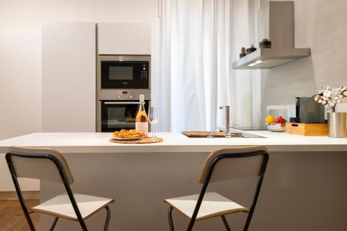 a kitchen with two chairs and a counter with a microwave at CASA ANTO - Charming apartment 50 meters from the beach in Alghero