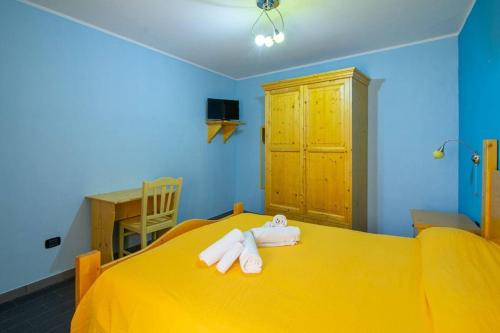 a bedroom with a yellow bed with towels on it at Al ViaVai in San Cosmo Albanese