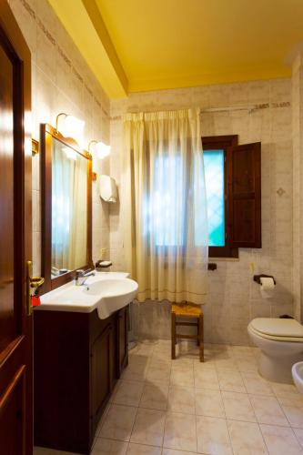 a bathroom with a sink and a toilet and a window at Fattoria Terra e Libertà in Contrada Maeggio