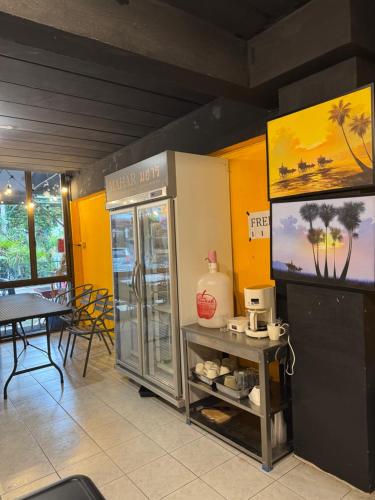 a restaurant with a refrigerator and a table with chairs at MaHar Hostel ChiangMai in Chiang Mai