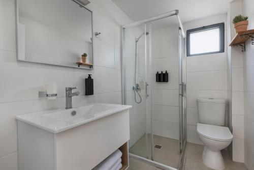a white bathroom with a sink and a toilet at Solaya Kineret in Migdal