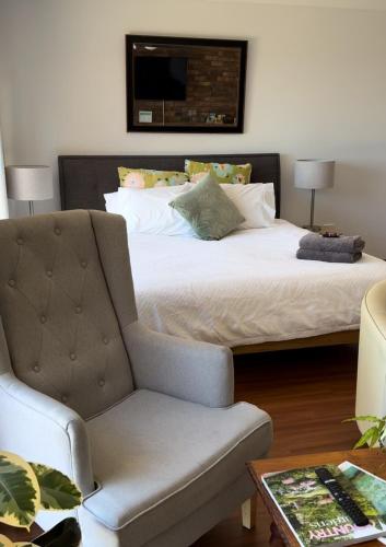 a bedroom with a bed with a chair and a couch at Darcy’s Ranch in Bathurst