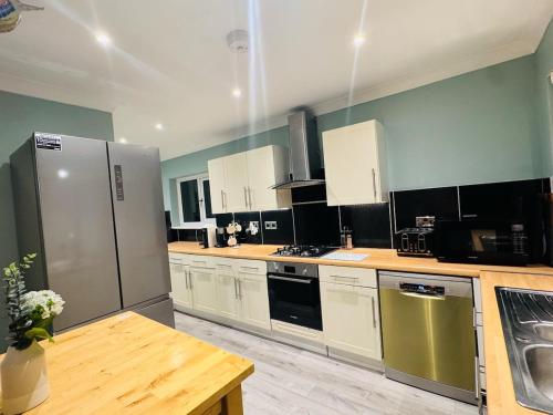 a large kitchen with white cabinets and stainless steel appliances at Modern 4BR House with Parking, 8 Mins to Gatwick Airport in Crawley