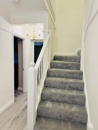 a staircase in a home with white walls and a chandelier at Modern 4BR House with Parking, 8 Mins to Gatwick Airport in Crawley