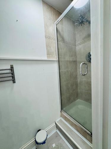 a shower with a glass door next to a toilet at Modern 4BR House with Parking, 8 Mins to Gatwick Airport in Crawley