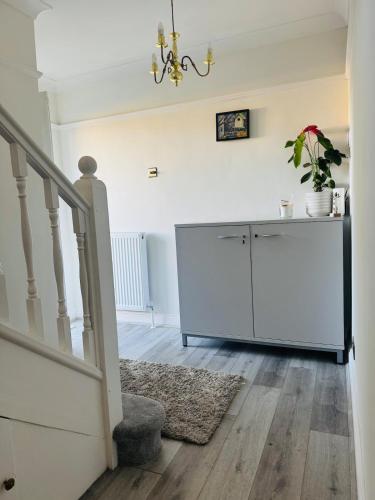 a room with a staircase and a white cabinet at Modern 4BR House with Parking, 8 Mins to Gatwick Airport in Crawley