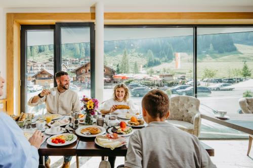 a group of people sitting around a table eating food at Hotel Salzburger Hof Zauchensee in Zauchensee