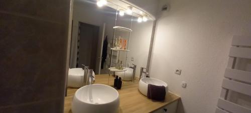 une salle de bain avec deux lavabos blancs et un miroir dans l'établissement 2 pièces, terrasses, place de parking en sous-sol, picentre saint gely du fesc, à Saint-Gély-du-Fesc