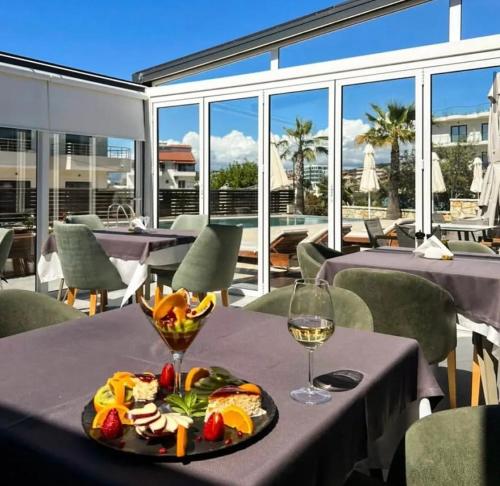 a table with a plate of food and a glass of wine at Blue Water Hotel Ksamil in Ksamil