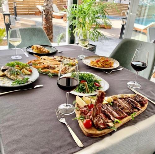 a table with plates of food and glasses of wine at Blue Water Hotel Ksamil in Ksamil