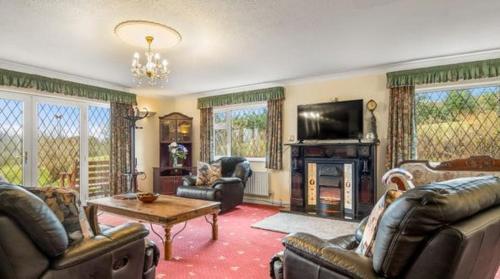 a living room with couches and a tv and a fireplace at Lake View House in Moyard