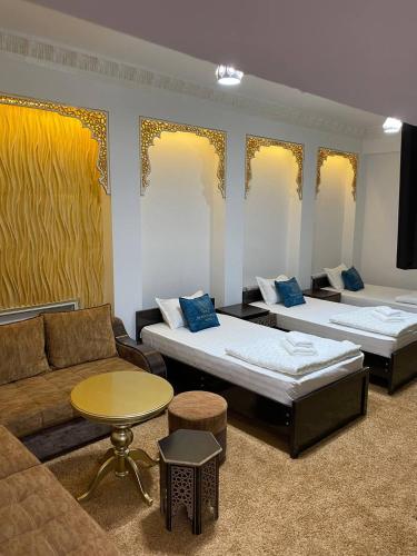 a room with two beds and a couch and a table at Mukhlisabegim Hotel in Bukhara