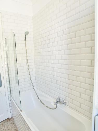 La salle de bains est pourvue d'une baignoire blanche avec un pommeau de douche. dans l'établissement Les Bananiers centre ville Cannes, à Cannes