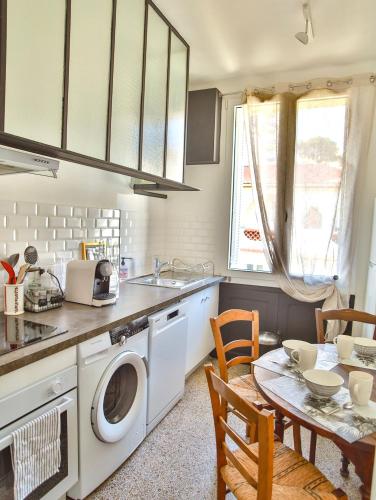 une cuisine avec une machine à laver et une table dans l'établissement Les Bananiers centre ville Cannes, à Cannes