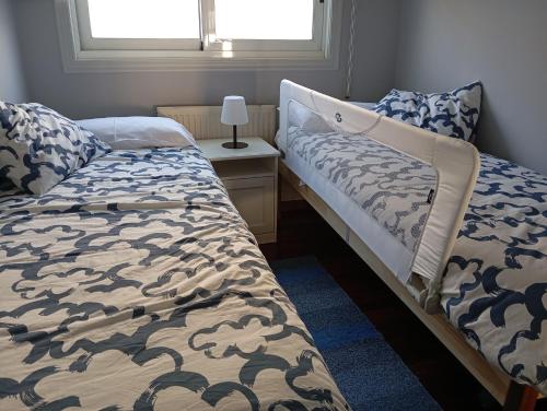 a bedroom with two beds and a table with a lamp at Hogar de Dulce in Vigo