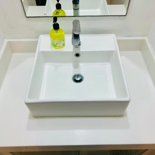 a white bathroom sink with a soap dispenser on it at Summer Suites KLCC By City Home Style in Kuala Lumpur