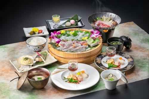 a table with plates of food and a bowl of food at 絶景海風癒し庵 新八屋 in Toba
