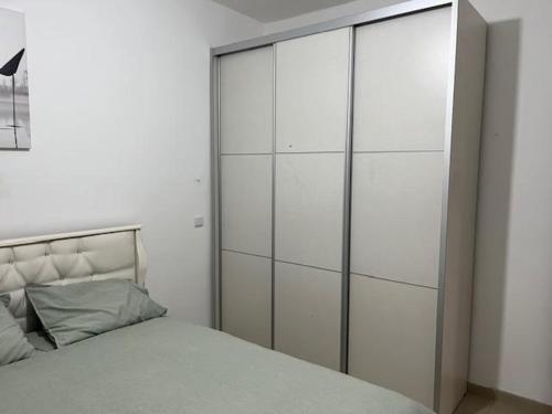 a bedroom with a large white cabinet next to a bed at פנינת הדגן 32 in El ‘Affūle
