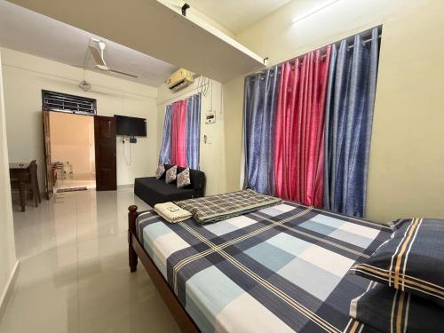 a bedroom with a bed and a couch and curtains at Ritu Heritage Homestay in Trivandrum