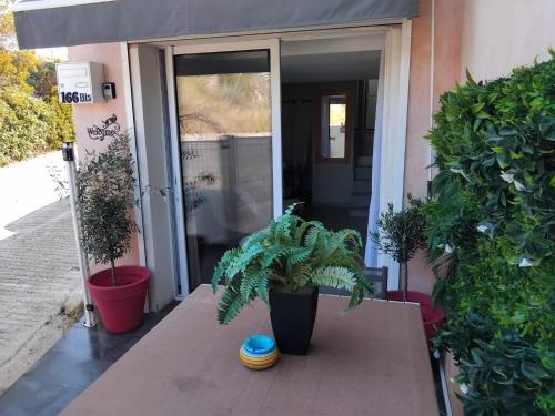 un tavolo in legno con piante davanti a una porta di BANDOL TYPE 2 AVEC TERRASSE et PARKING a Bandol