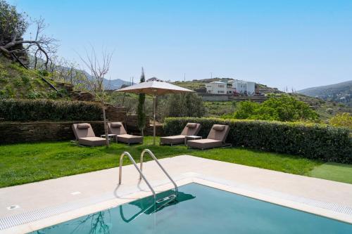 a swimming pool with chairs and an umbrella at SuiteHome Villas with Private Pools by Explore Andros in Andros