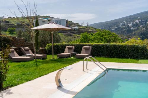 a swimming pool with lounge chairs and an umbrella at SuiteHome Villas with Private Pools by Explore Andros in Andros