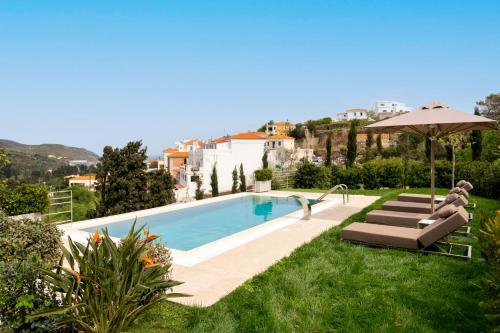 a pool with two lounge chairs and an umbrella at SuiteHome Villas with Private Pools by Explore Andros in Andros