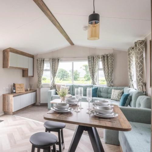 a living room with a table and a blue couch at Gimblet Rock Holiday Park in Pwllheli