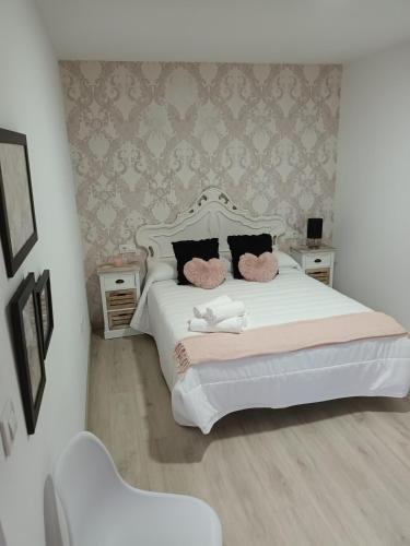 a bedroom with a white bed with two pink pillows at Él Rincón de los Sueños A in Vegadecabo