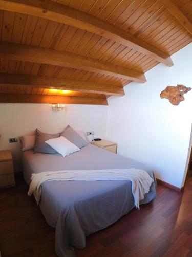 a bedroom with a large bed with wooden ceilings at Hotel Rural L'Ortiga Blanca in Queralbs