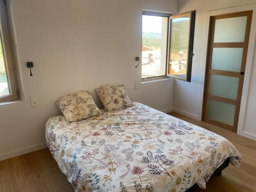 a bedroom with a bed with a floral comforter and two windows at Gîte lumineux avec jardin, vue sur Peyrepertuse in Rouffiac-des-Corbières