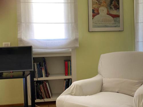 a living room with a white chair and a tv at Coloniola Lake House in Como