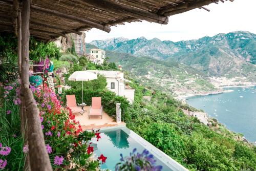 a swimming pool with flowers and a view of the water at Villa San Cosma in Ravello