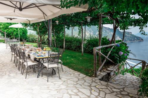 a long table with chairs and an umbrella and water at Villa San Cosma in Ravello