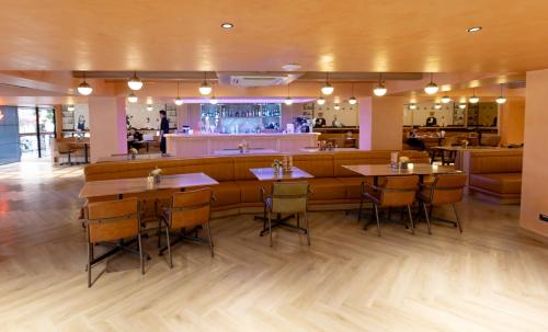 a restaurant with wooden tables and chairs and a bar at Myhotel Cmyk@Ratchada in Bangkok
