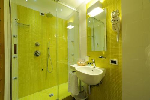 a bathroom with a sink and a shower with yellow tiles at Hotel Le Roi in Varazze