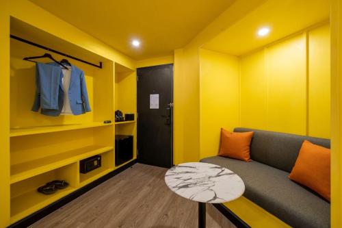 a yellow living room with a couch and a table at Myhotel Cmyk@Ratchada in Bangkok
