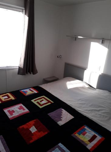 une chambre avec un lit avec une couette dessus dans l'établissement Mobil home entre mer et forêt, à Camiers