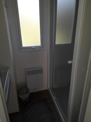 La petite salle de bains est pourvue d'une douche et d'une fenêtre. dans l'établissement Mobil home entre mer et forêt, à Camiers