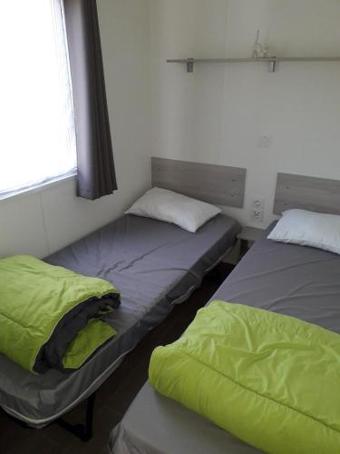 deux lits assis dans une pièce avec une fenêtre dans l'établissement Mobil home entre mer et forêt, à Camiers