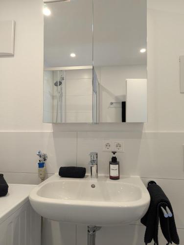 a white bathroom with a sink and a mirror at Apartment del Mardy in Ostfildern