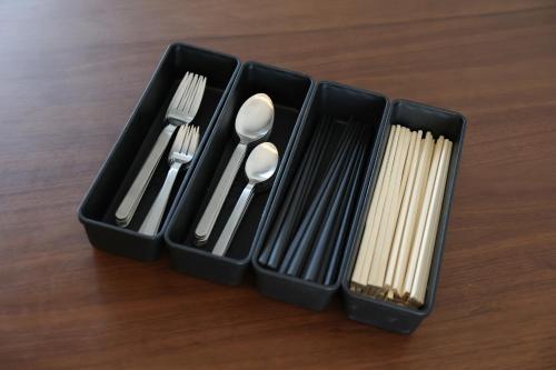 four plastic utensils in black containers on a table at Ayumi STAY 駐車1台のみ in Sapporo